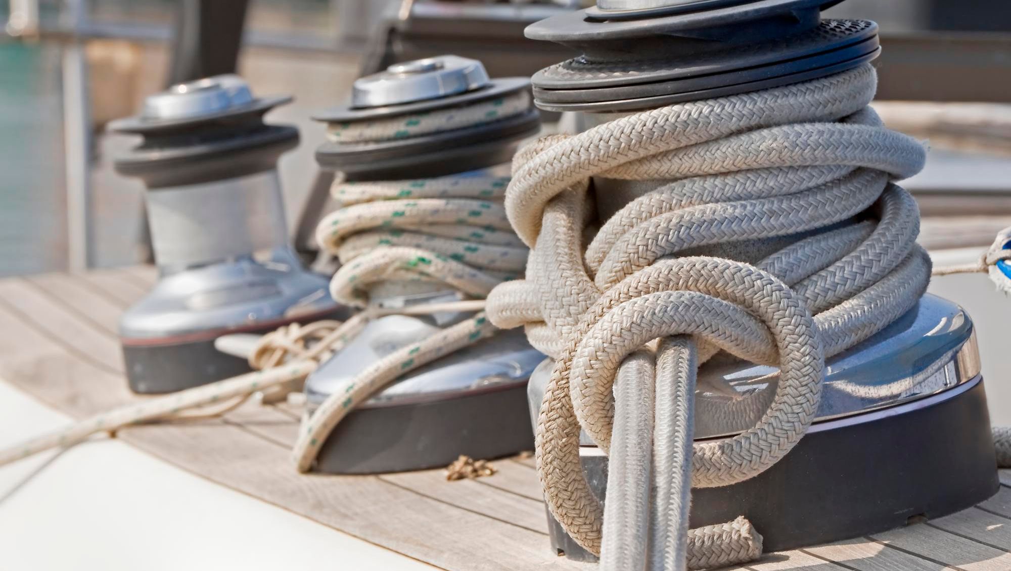 Tau surret rundt vinsj på seilbåtdekk i sollys.